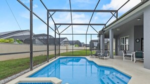 Une piscine dotée d’une zone couverte, entourée d’une clôture et jouxtant un bâtiment avec un espace extérieur aménagé pour s’asseoir.