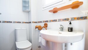 A bathroom with a toilet, sink, and decorative tiles. - Casa Noray         . (La Isleta del Moro)