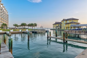 A waterfront property with a dock, a row of palm trees, and a building with multiple balconies.