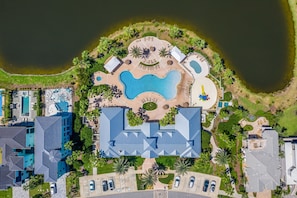 An aerial view of a resort with a central swimming pool, multiple guest buildings, and surrounding greenery.