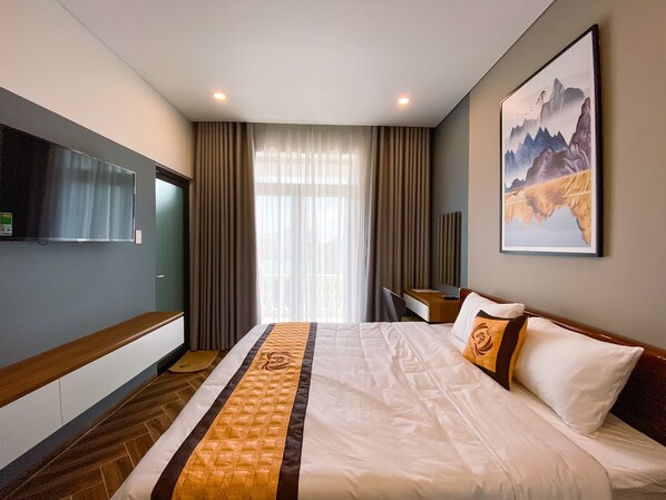 Una habitación de hotel con una cama grande, un escritorio, un televisor y un cuadro en la pared.