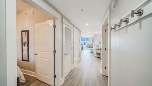 Un couloir avec des portes blanches, un plancher en bois et une vue sur un espace de vie comprenant un canapé et une table.