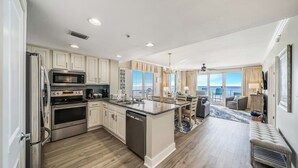 Une cuisine spacieuse, dotée d’appareils électroménagers modernes, d’un grand îlot central et offrant une vue sur l’extérieur.