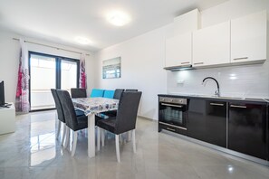 Una cocina moderna con armarios blancos, una estufa negra y un comedor con mesa y sillas.