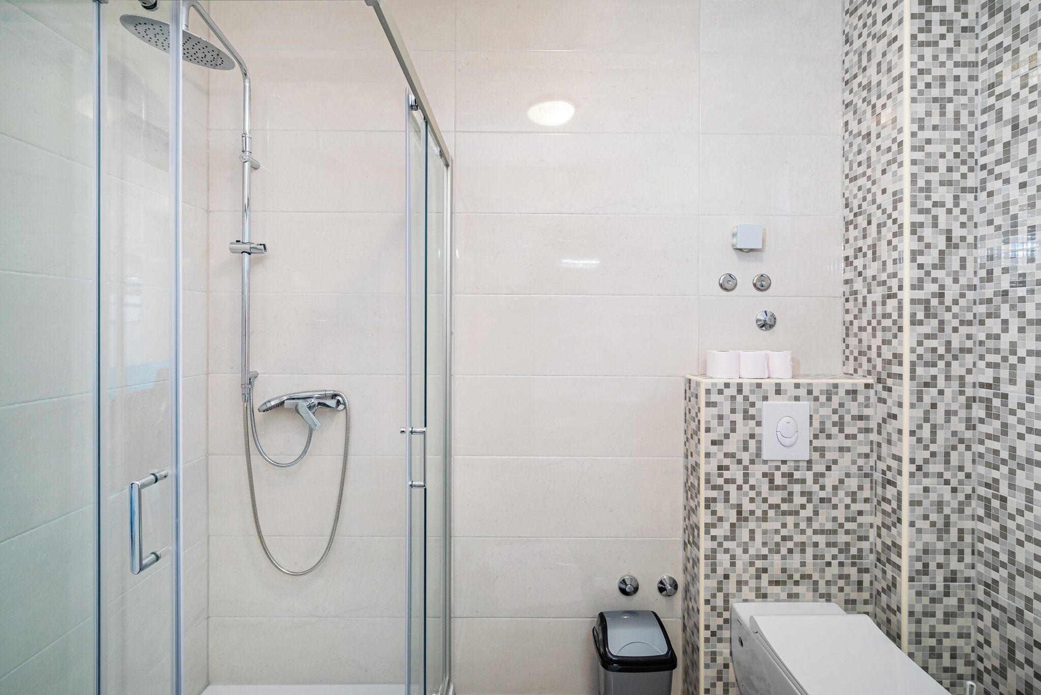 A modern bathroom with a glass-enclosed shower, a toilet, and a sink.