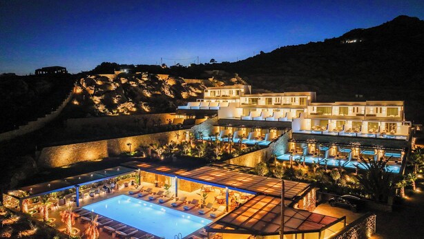 A multi-story hotel with outdoor pools, lounge areas, and a mountainous backdrop. - Muse of Mykonos  (Mykonos)