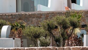 A modern white building with multiple balconies, set against a rocky hillside. - Muse of Mykonos  (Mykonos)