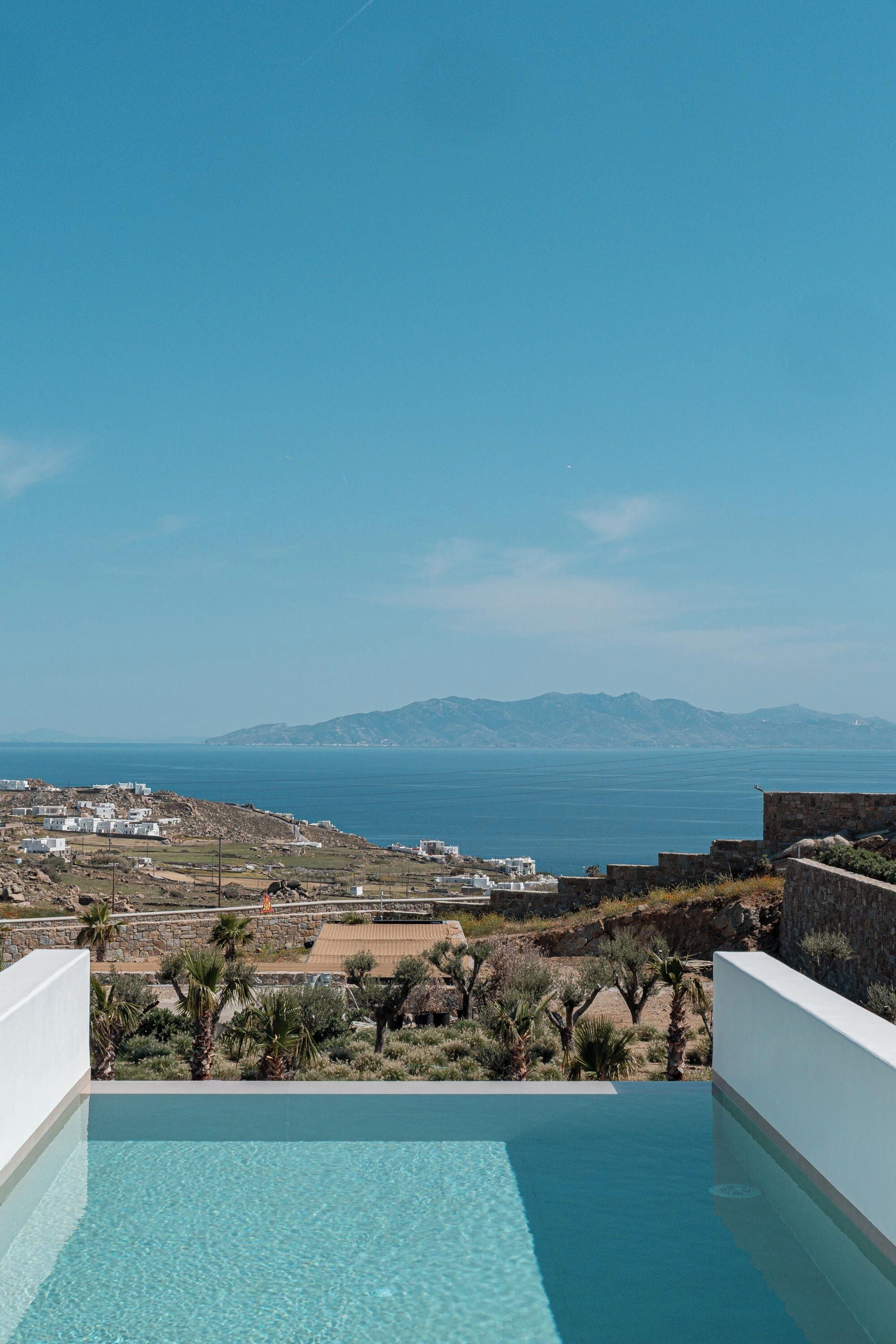 An infinity pool with a view of the sea and distant mountains.