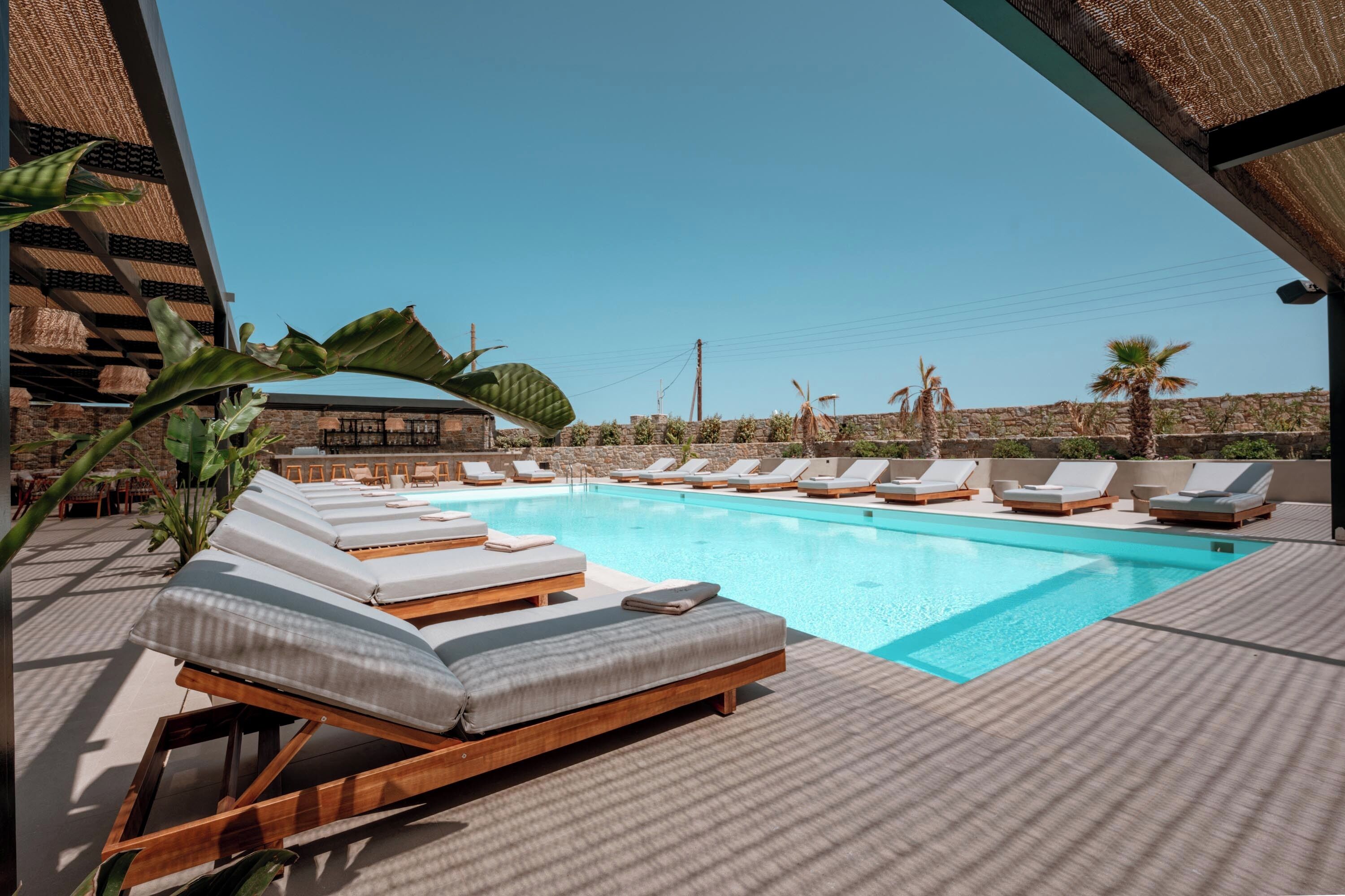 Un área junto a la piscina con sillas de descanso y una piscina azul cristalina.