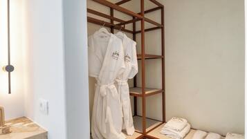 Un baño moderno con tocador de madera, estante empotrado con batas y un perchero para toallas.