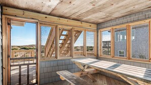 A wooden deck with a picnic table, large windows, and a view of the landscape.