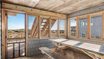 A wooden deck with a picnic table, large windows, and a view of the landscape.