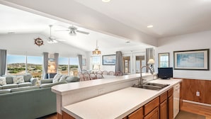 A spacious living area with a large island kitchen, wooden cabinets, and a ceiling fan.