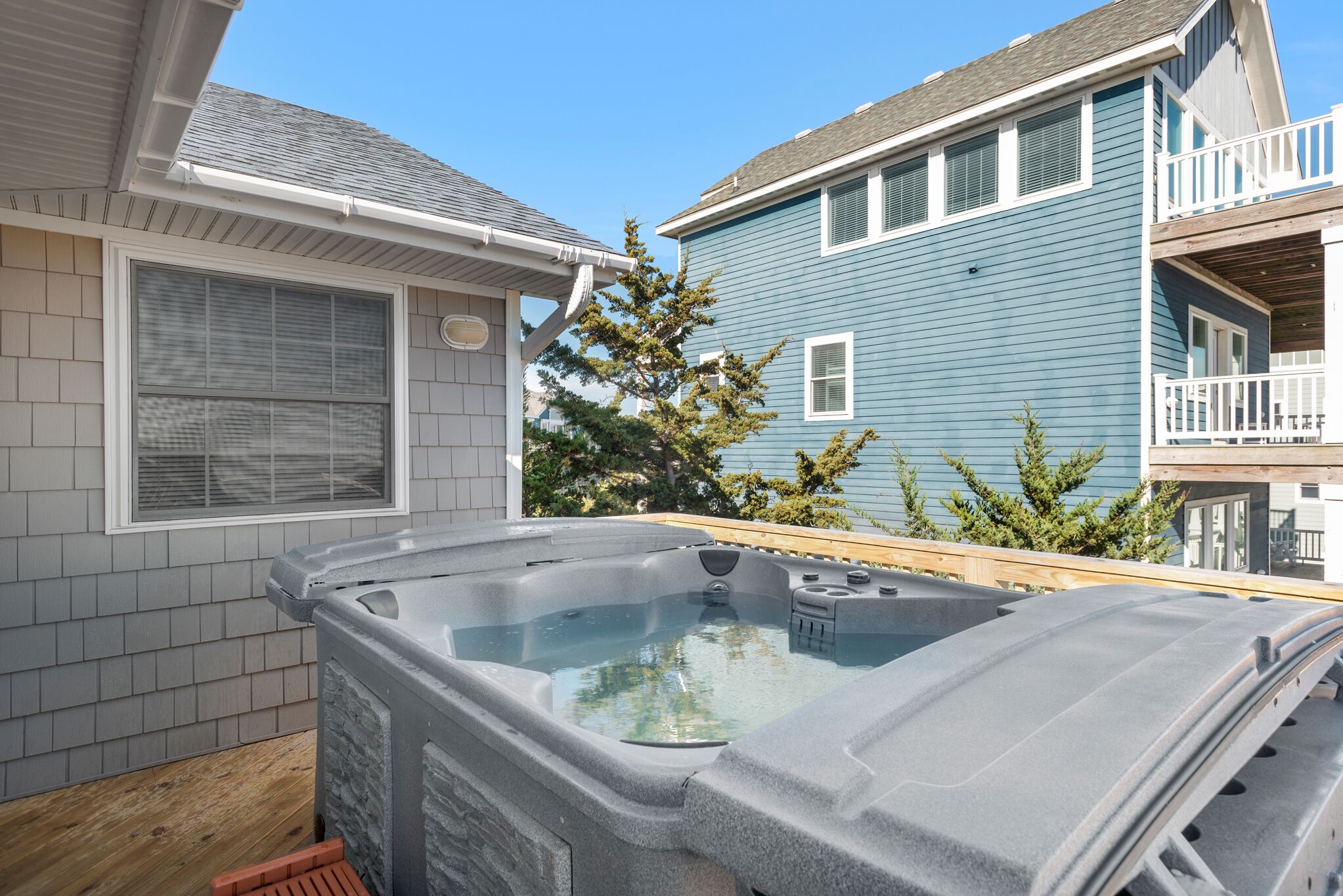 A hot tub in a backyard with a house in the background.