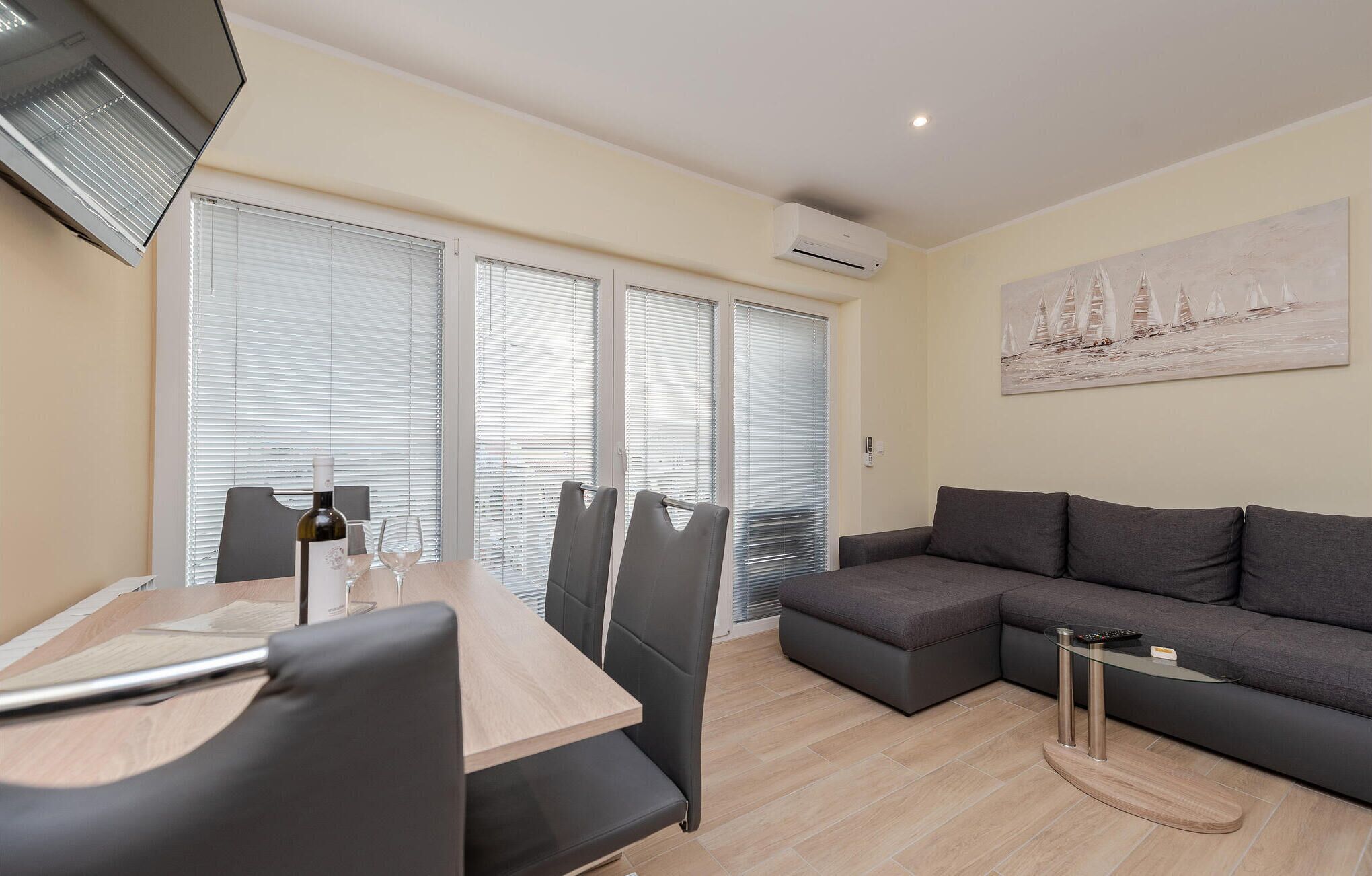 A modern living room with a dining area, featuring a sofa, a dining table with chairs, and a painting on the wall.