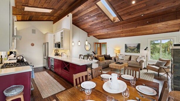 Eine geräumige Küche mit Kochinsel, Holzboden und großen Fenstern.