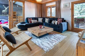 Una sala de estar acogedora con un sofá de color oscuro, una mesa de centro de madera y sillones de mimbre.