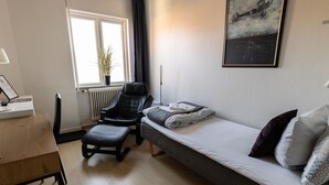 A compact room with a bed, a desk, a chair, and a radiator. - Hotel Rønne H (Ronne)
