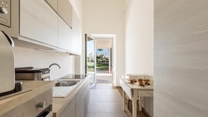 A modern kitchen with a built-in oven, a stovetop, and a sink. There is a window providing a view of the outdoors. - 3675 Dimora Seculari by Perle di Puglia (Mesagne)