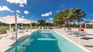 A rectangular swimming pool with clear blue water, surrounded by white lounge chairs and a large white canopy. - 3675 Dimora Seculari by Perle di Puglia (Mesagne)