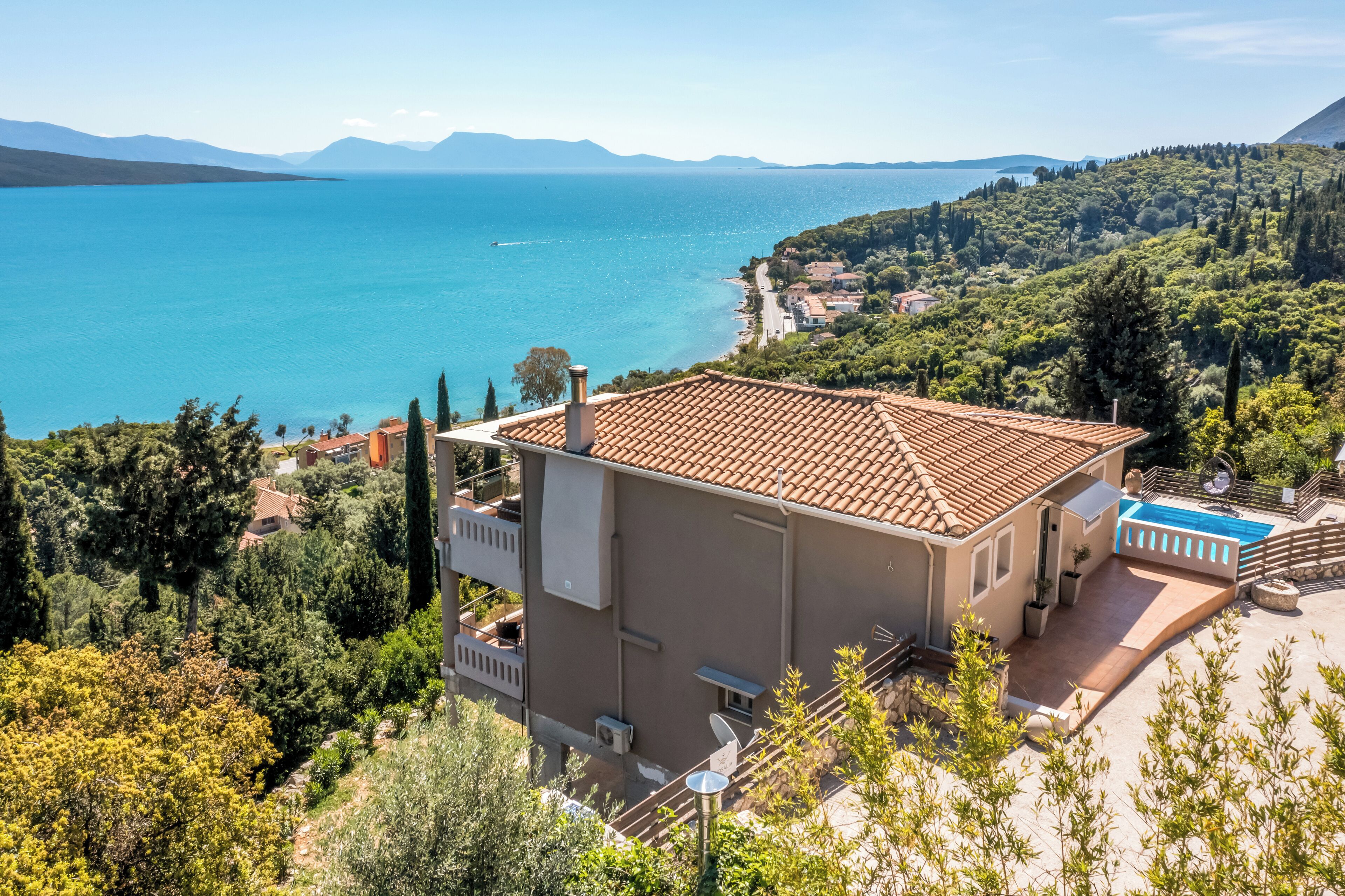 Une villa de style méditerranéen, dotée d’un toit en tuiles, d’une piscine et offrant une vue sur la mer et les montagnes.