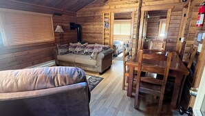 A cozy cabin interior with a sofa, a dining table, and a fireplace. - Beautiful 2 Bedroom Cabin on Taylor River with Private Hot Tub (Almont)