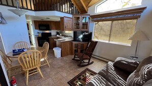 Un salón amplio con mesa de comedor, sillas de madera, un sofá y una cocina al fondo.