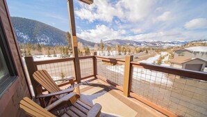 Un balcon avec des chaises en bois et une vue sur un paysage montagneux enneigé.