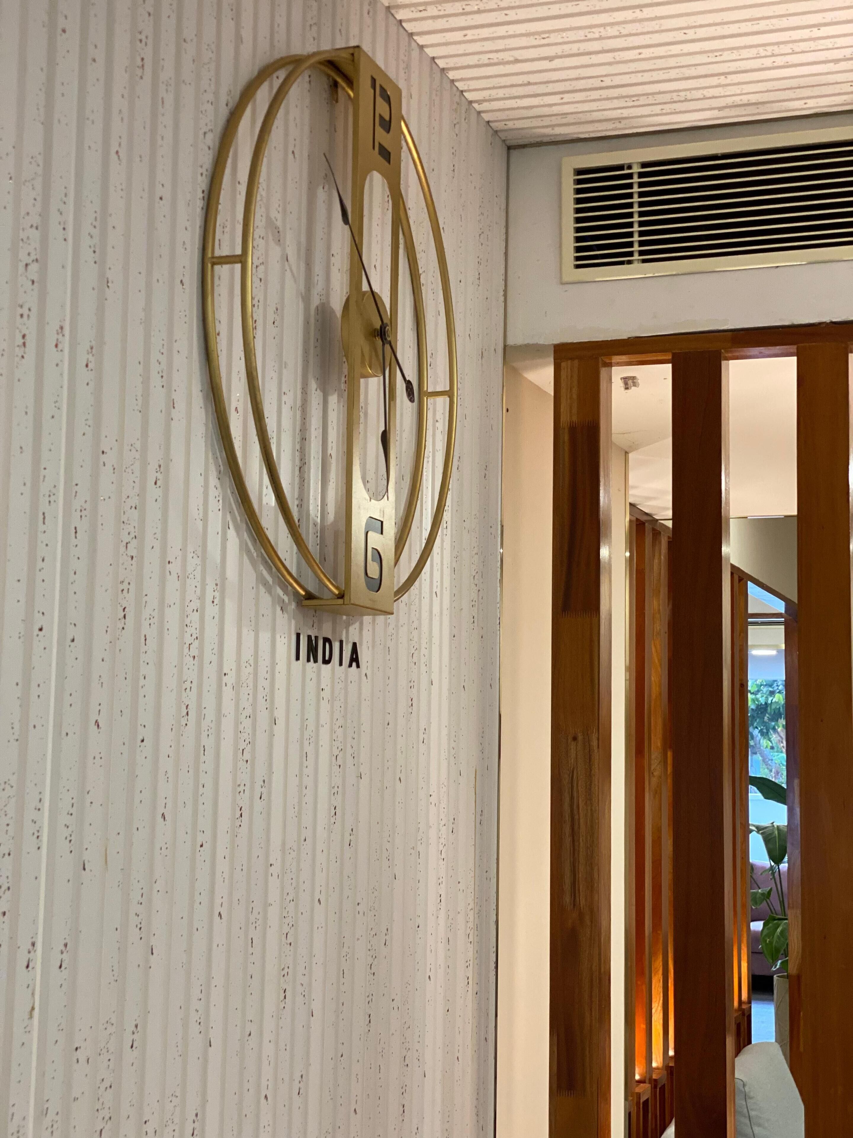 A wall-mounted clock with the number 12 and the word "INDIA" below it.