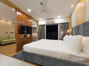 Una habitación de hotel moderna con una cama grande, televisión, ventilador de techo y aire acondicionado.