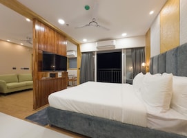 Una habitación de hotel moderna con una cama grande, televisión, ventilador de techo y aire acondicionado.
