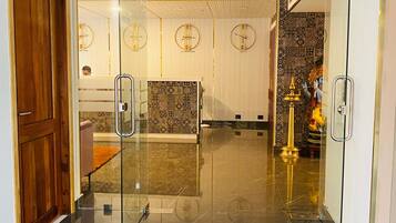 A lobby with a glass door, a wooden door, a tiled floor, and clocks on the wall.