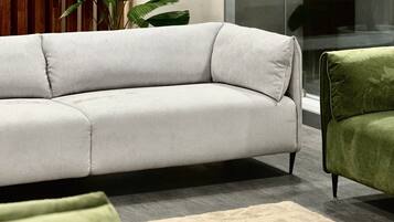 Una sala moderna con un sofá gris, un sillón verde y una planta grande en maceta.