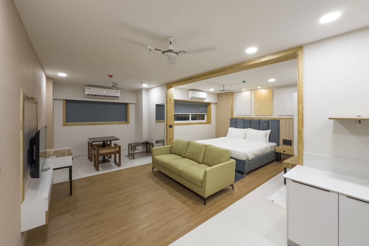 A modern hotel room with a bed, a sofa, a desk, and a ceiling fan.