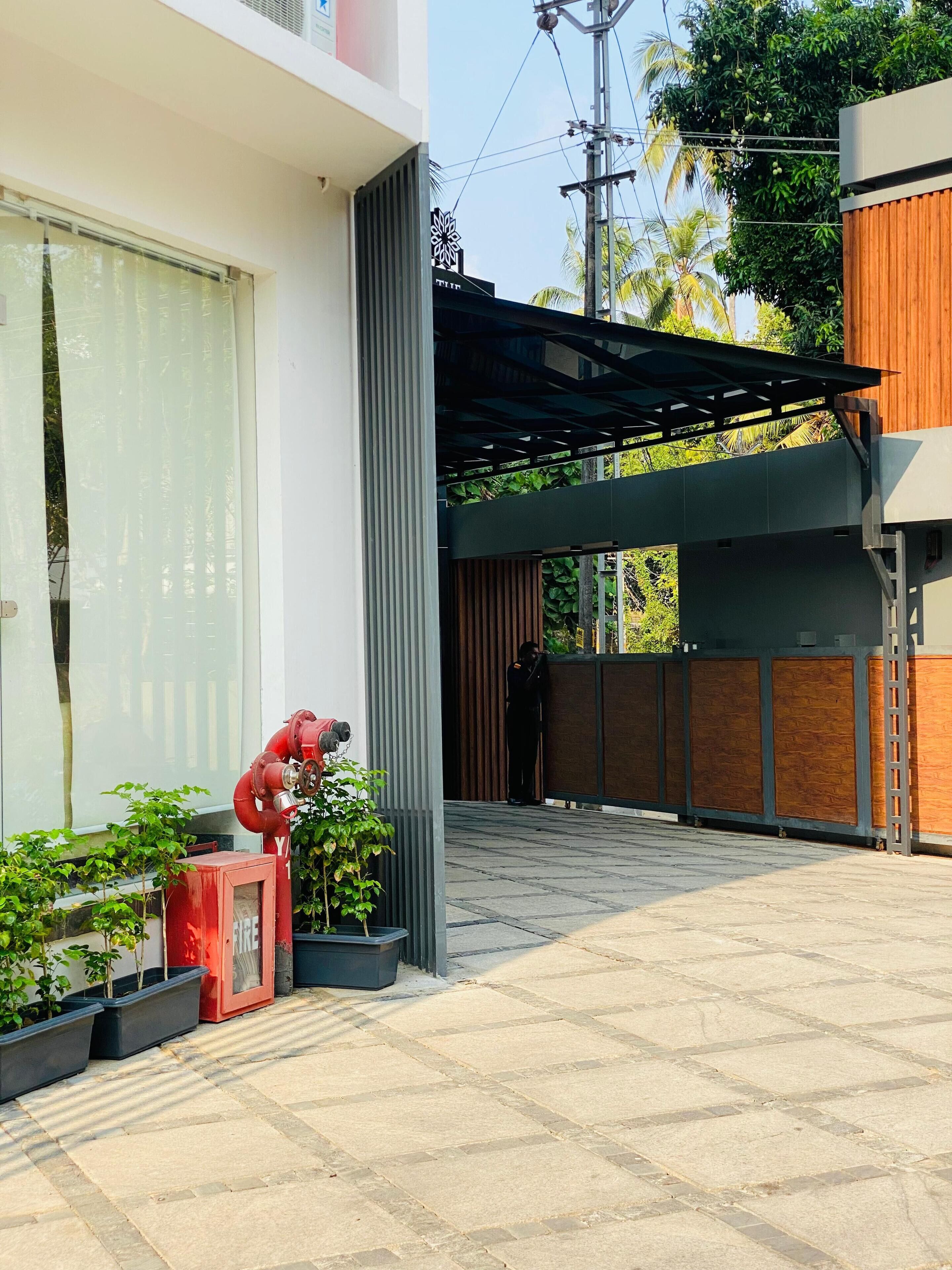 A modern building with a covered outdoor area, a fire hydrant, and potted plants.