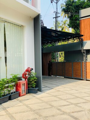 A modern building with a covered outdoor area, a fire hydrant, and potted plants. - 7 Apple Hotel Guruvayur, Kerala (Chavakkad)
