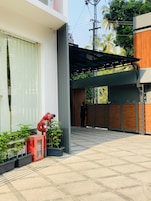 Um edifício moderno com área externa coberta, hidrante e plantas em vasos.