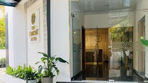 A hotel entrance with a glass door, a sign reading "The Elegant Suites", and a potted plant in front. - 7 Apple Hotel Guruvayur, Kerala (Chavakkad)