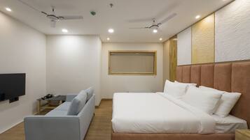 A modern bedroom with a bed, a sofa, a TV, and two ceiling fans.