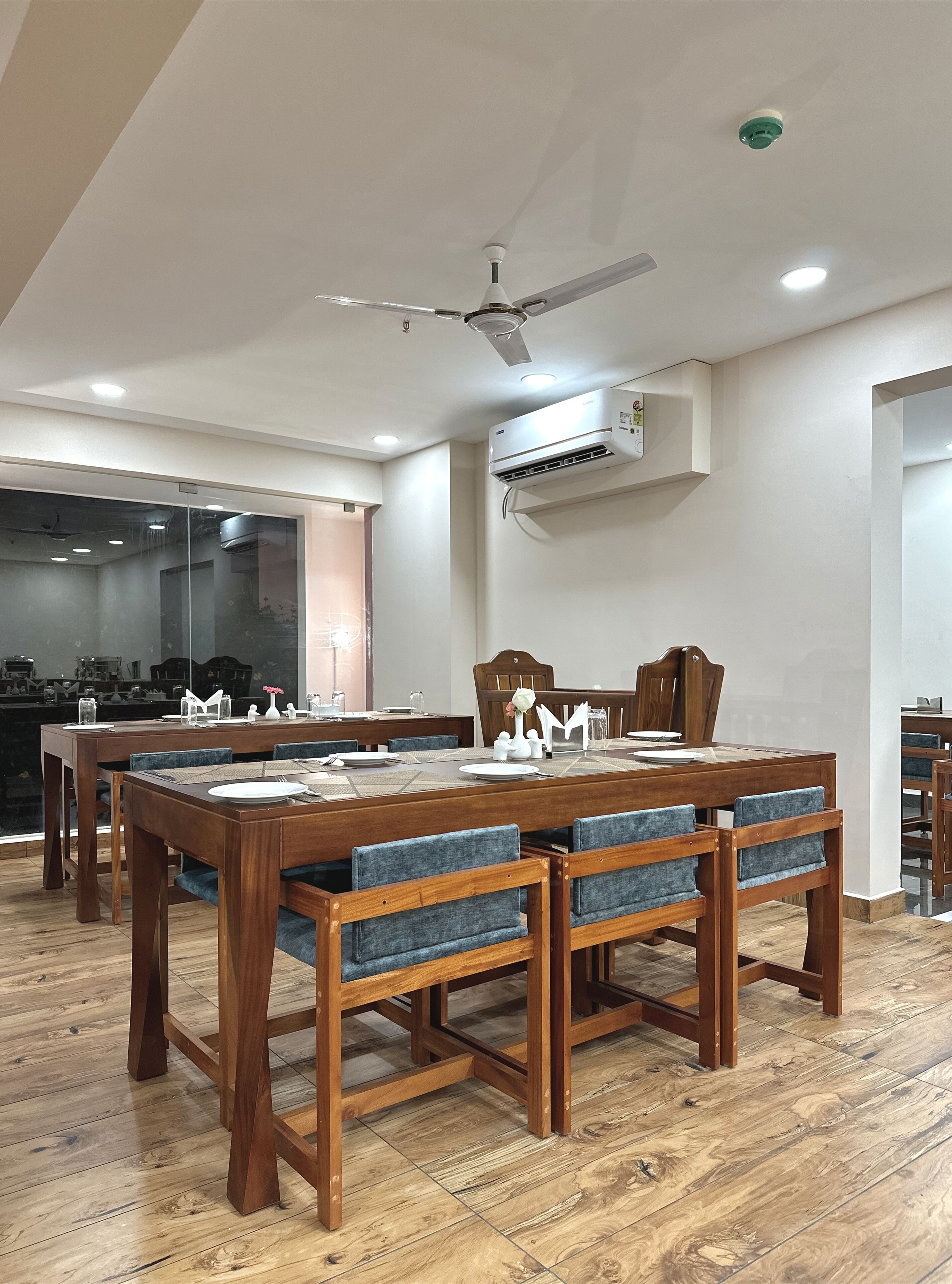 A dining area with a wooden table and chairs, an air conditioning unit, and a ceiling fan.