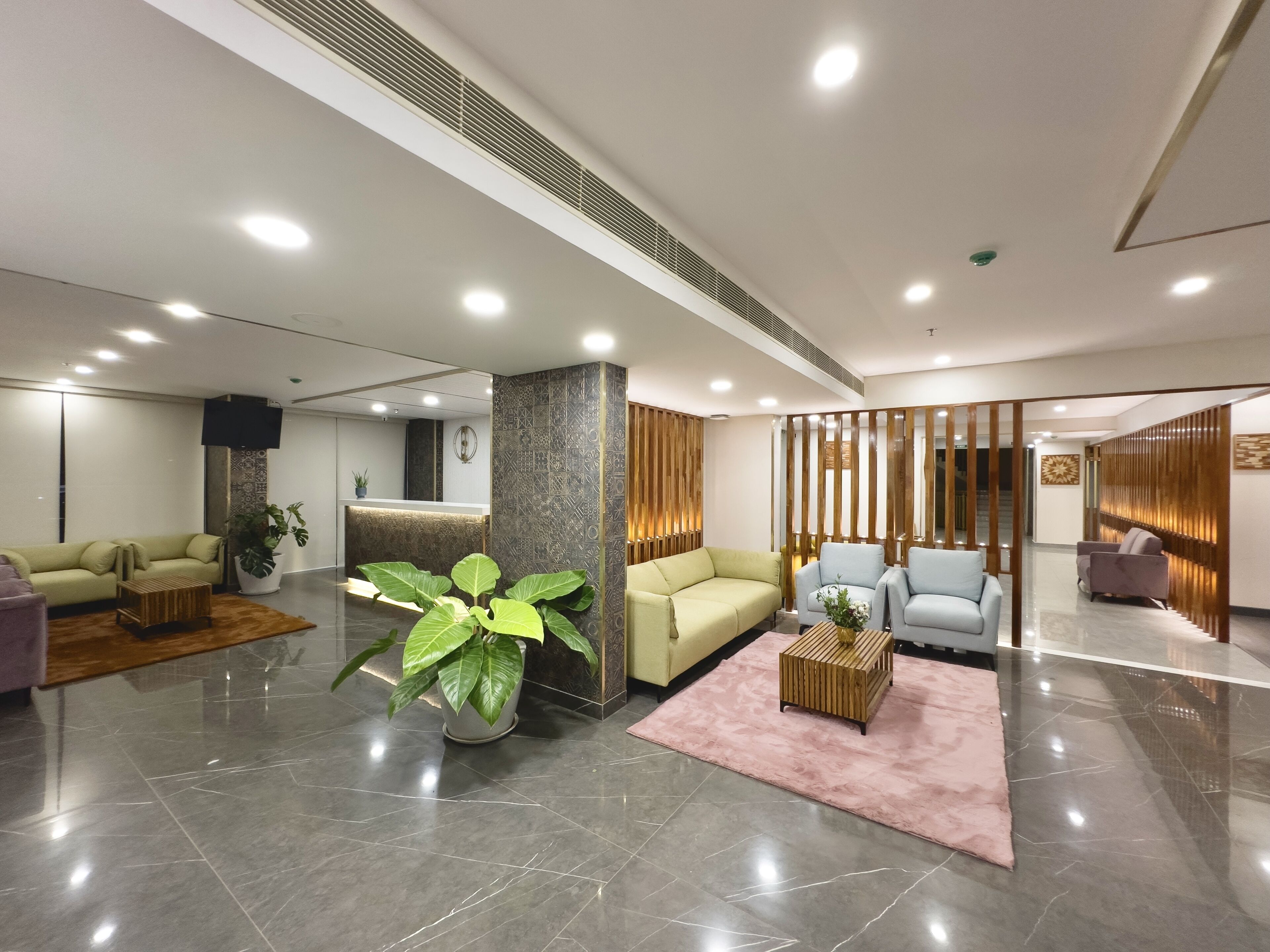 A modern lobby with a reception desk, seating area, and a large potted plant.