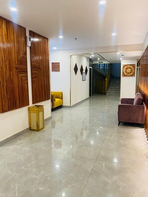 A hotel lobby with a polished marble floor, wooden paneling on the walls, and a staircase leading to the upper floors. - 7 Apple Hotel Guruvayur, Kerala (Chavakkad)