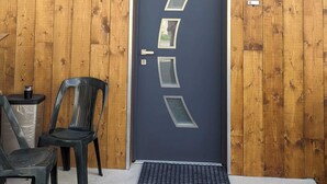 Parede exterior de madeira com uma porta azul escura e recortes geométricos.