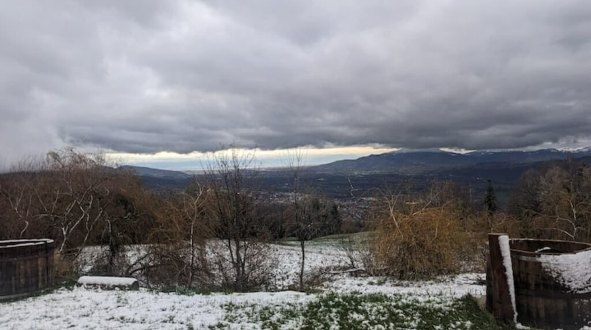 Eine verschneite Landschaft mit Blick auf ferne Berge und einem bewölkten Himmel.