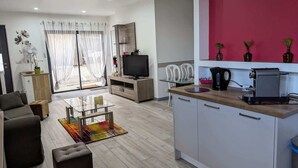 Uma sala de estar moderna com uma mesa de centro de vidro, um sofá e uma televisão.