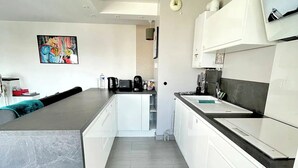 Una cocina moderna con armarios blancos, una encimera negra y un lavavajillas empotrado.