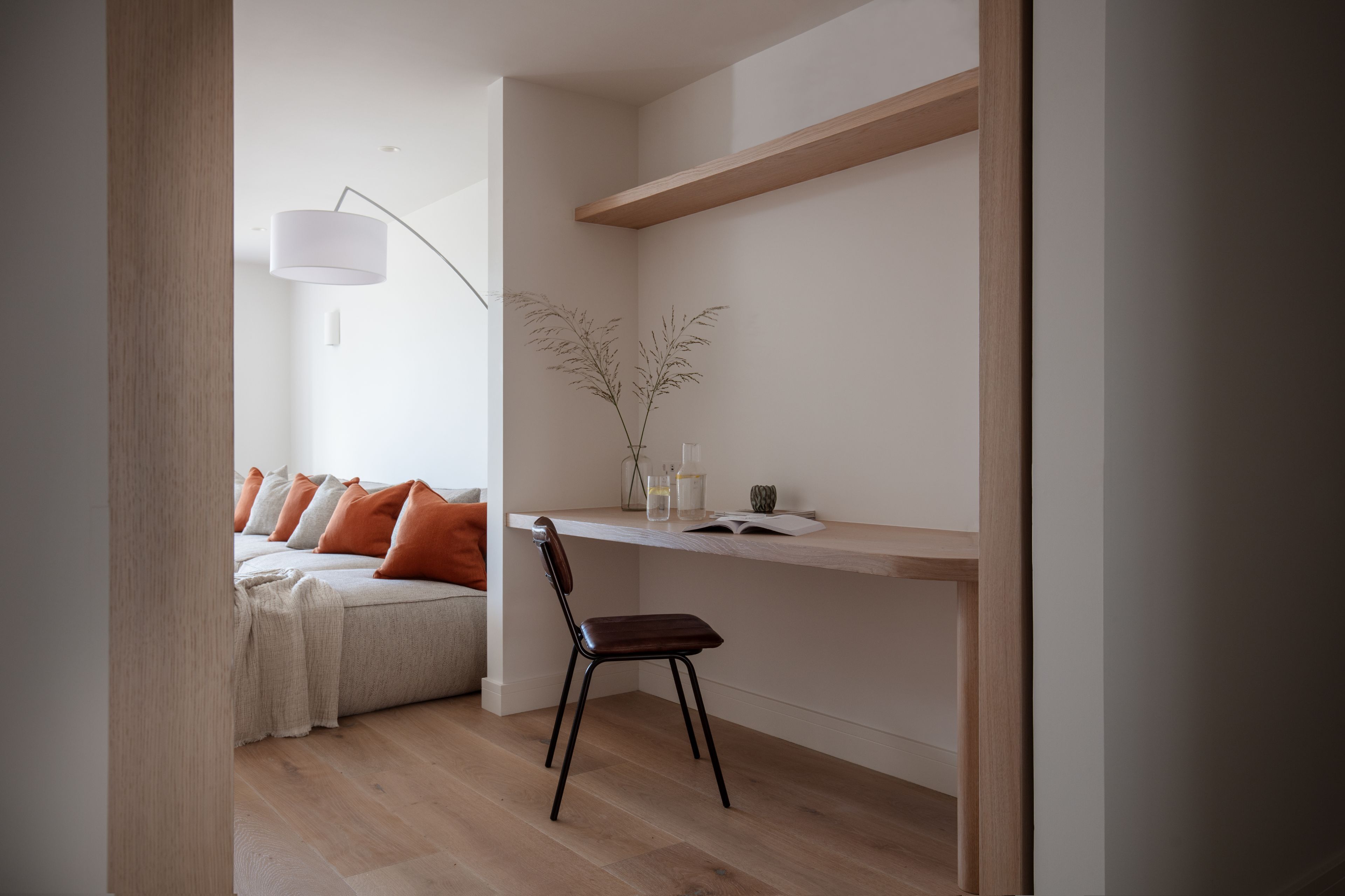 A modern, minimalist room with a bed, a desk, and a chair.