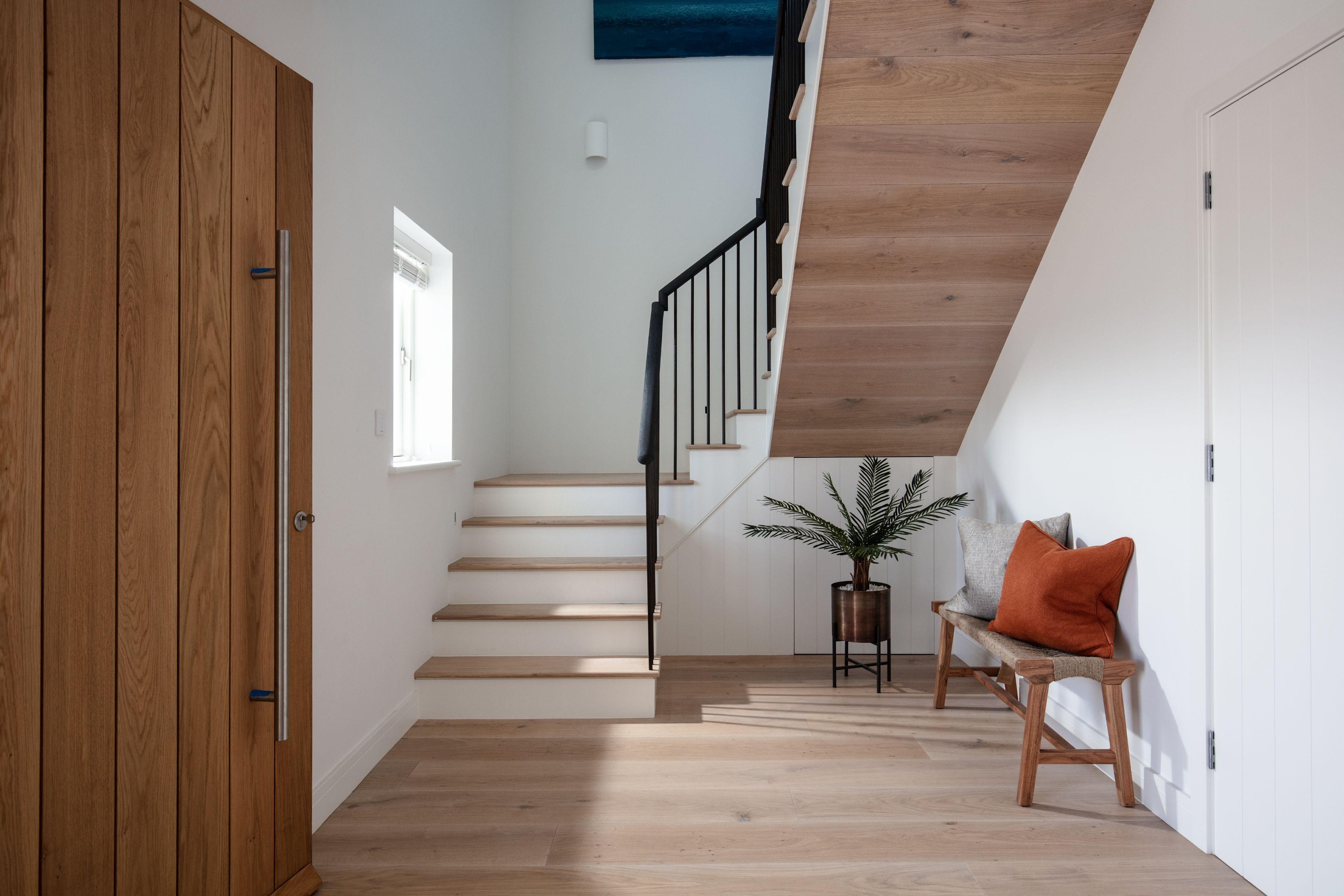 Un escalier menant à l’étage supérieur, avec des rampes en bois et un pot de fleurs placé à sa base.