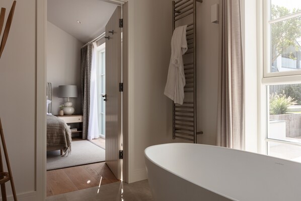 Ein modernes Badezimmer mit freistehender Badewanne, einem Handtuchhalter und einem sichtbaren Duschbereich.