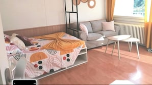 A room with a bed, a sofa, a small table, and a radiator. - Apartment Cosy annemasse (Annemasse)
